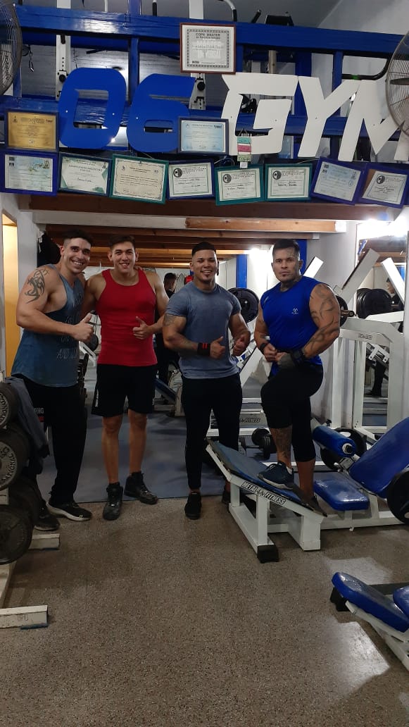 El equipo de 06-GYM bajo el cartel del gimnasio, con reconocimientos y certificaciones en la pared